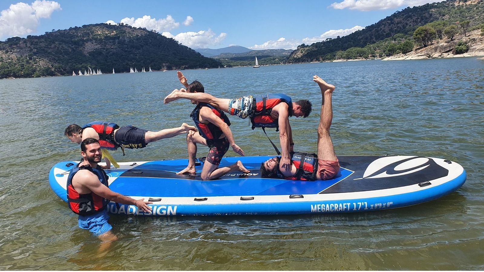 Compañeros haciendo el pino sobre una tabla hinchable en el pantano